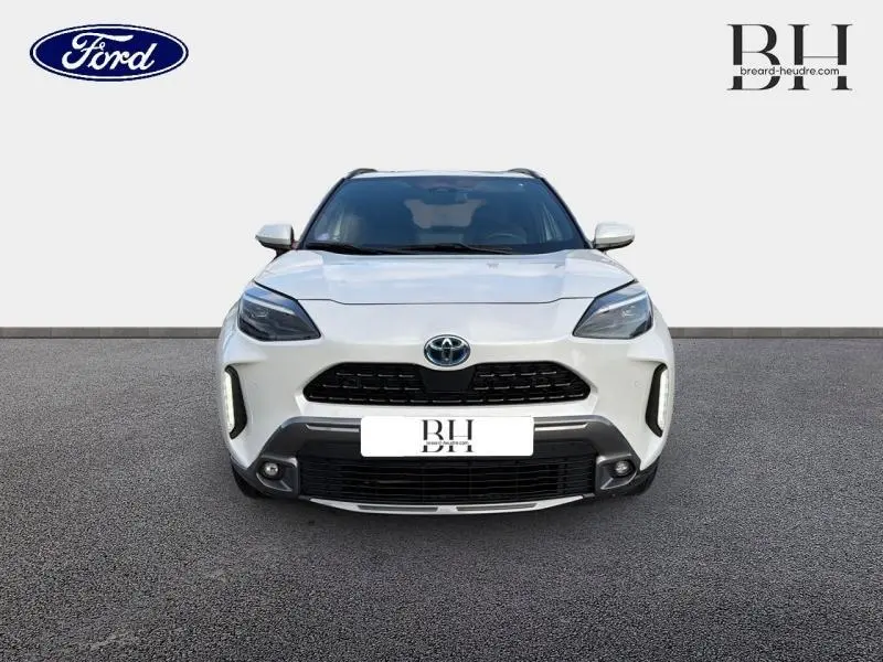 Vue frontale d'un Toyota Yaris Cross blanc lunaire nacré avec calandre noire et phares LED distinctifs.