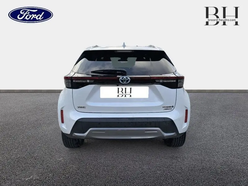 Vue arrière d'une Toyota Yaris Cross 116h Trail AWD-i blanche nacrée avec feux arrière LED et lunette arrière surteintée.