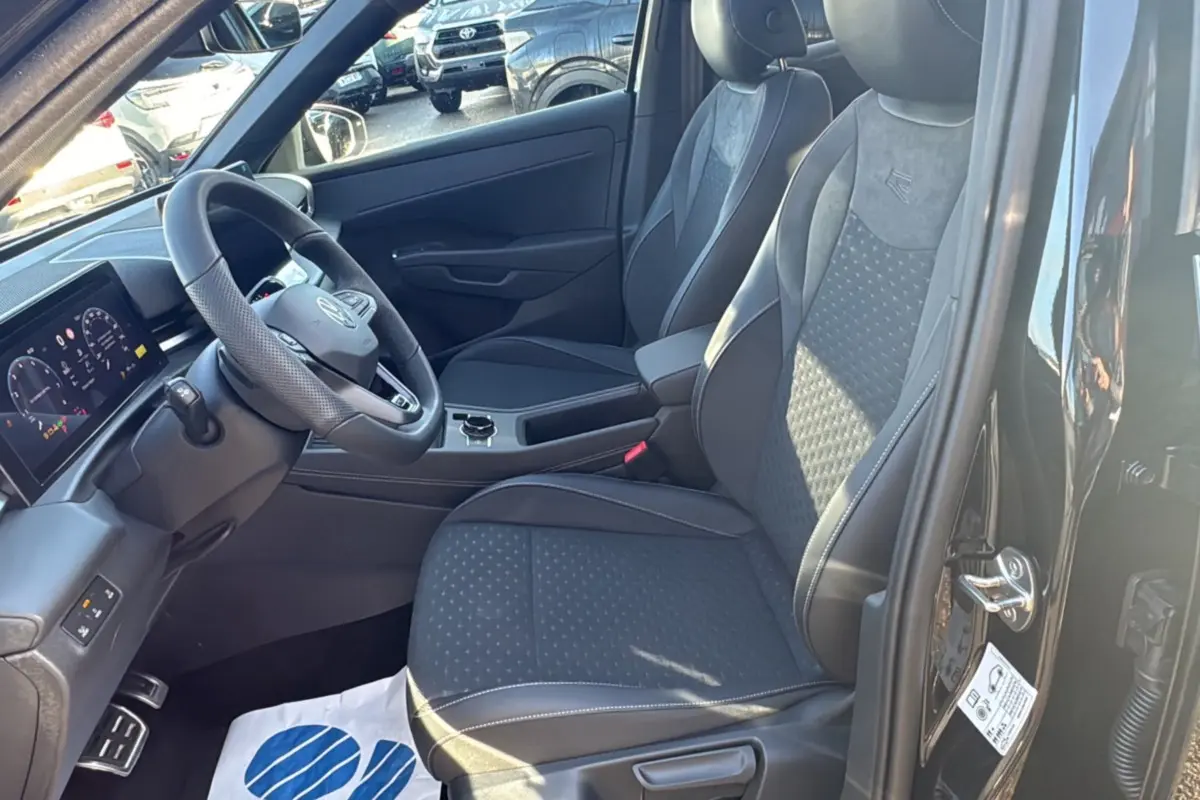 Intérieur du Volkswagen T-Roc noir, vue côté conducteur, sièges tissu R-Line et volant cuir multifonctions.