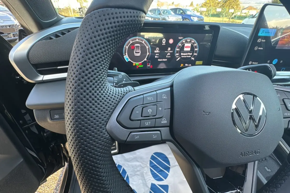 Vue rapprochée du volant multifonctions en cuir perforé et du tableau de bord numérique du Volkswagen T-Roc noir ebène 2026.