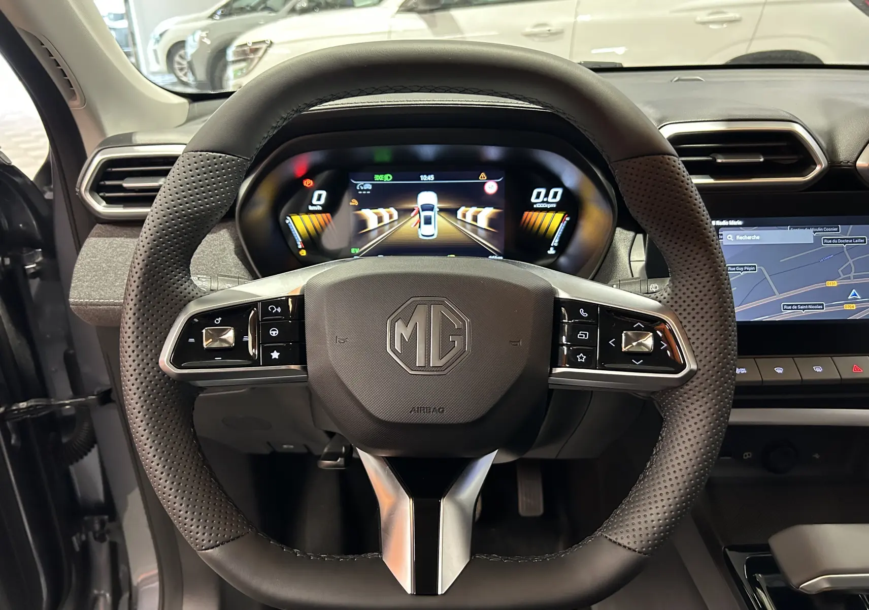 Vue intérieure centrée sur le volant perforé et le tableau de bord numérique du MG ZS Hybrid+ 2025 en Hampstead Grey.