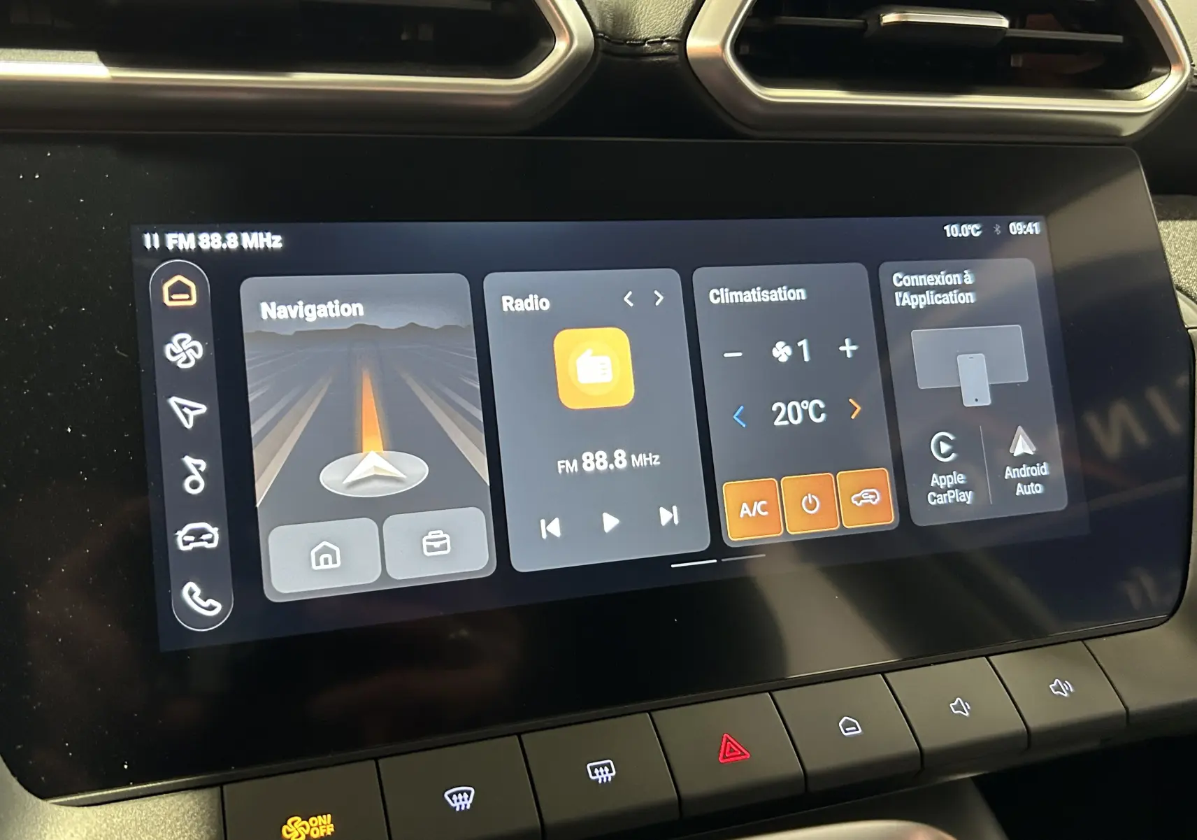 Écran tactile central du MG ZS Hybrid+ 2025 montrant navigation, radio FM, climatisation à 20°C et options Apple CarPlay/Android Auto.