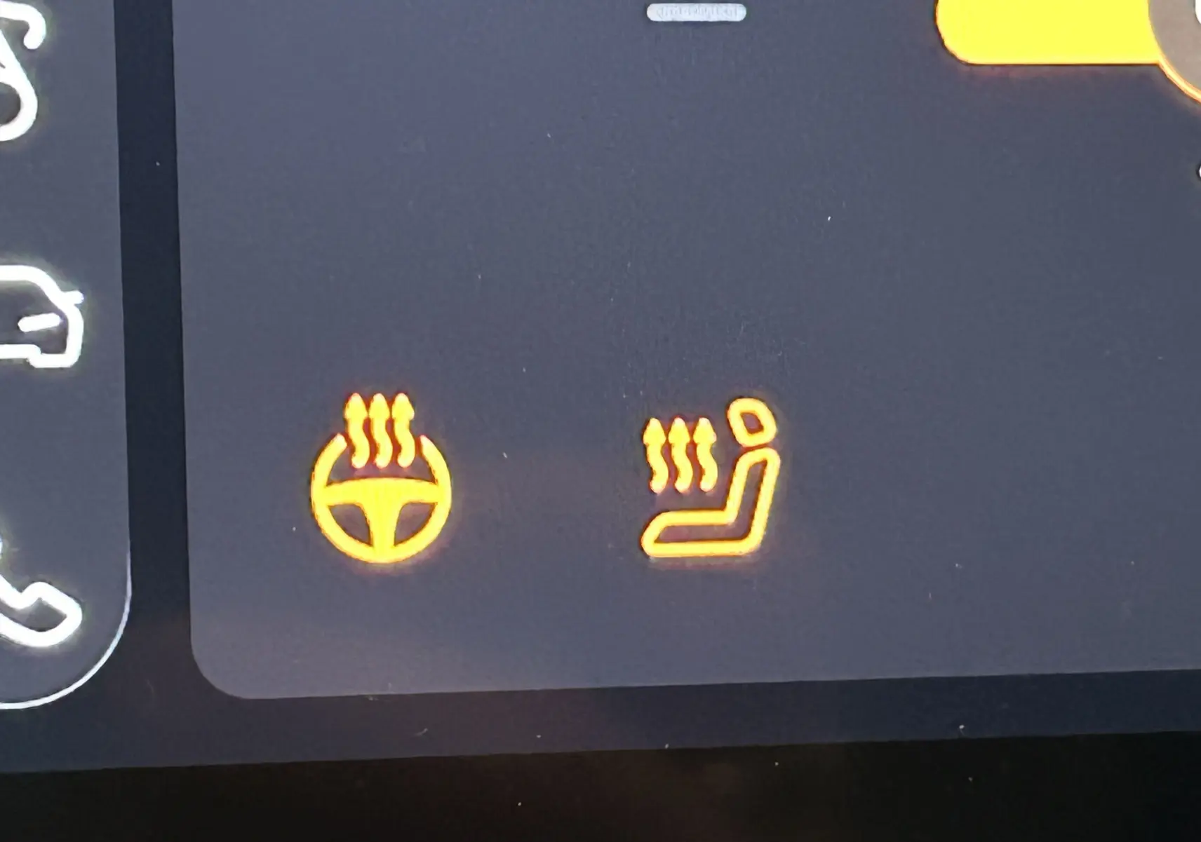 Gros plan sur l'écran du tableau de bord du MG ZS Hybrid+ 2025 montrant les icônes de volant et siège chauffants.