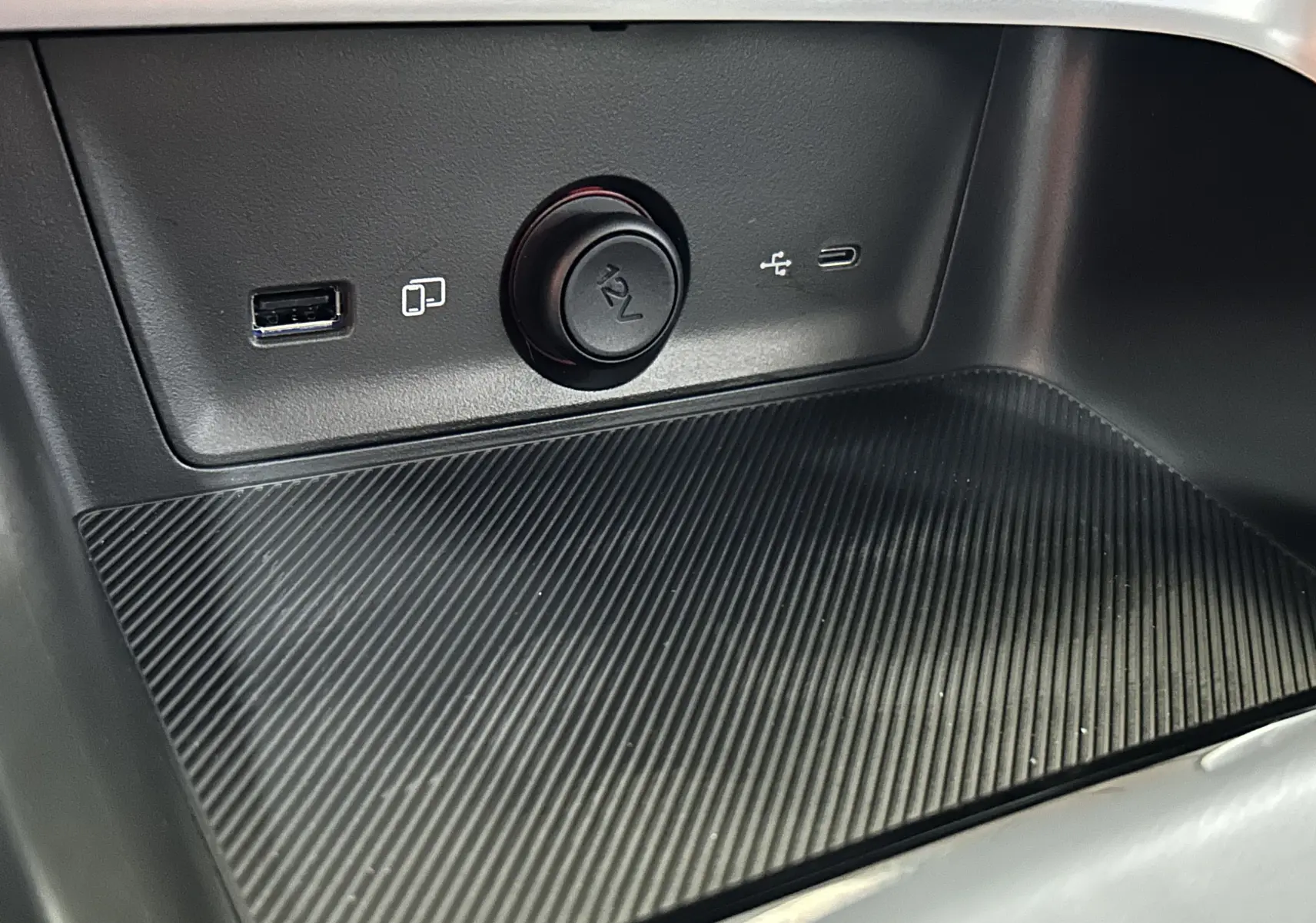 Gros plan sur la console centrale du MG ZS Hybrid+ 2025 montrant prises USB, prise 12V et surface texturée noire.