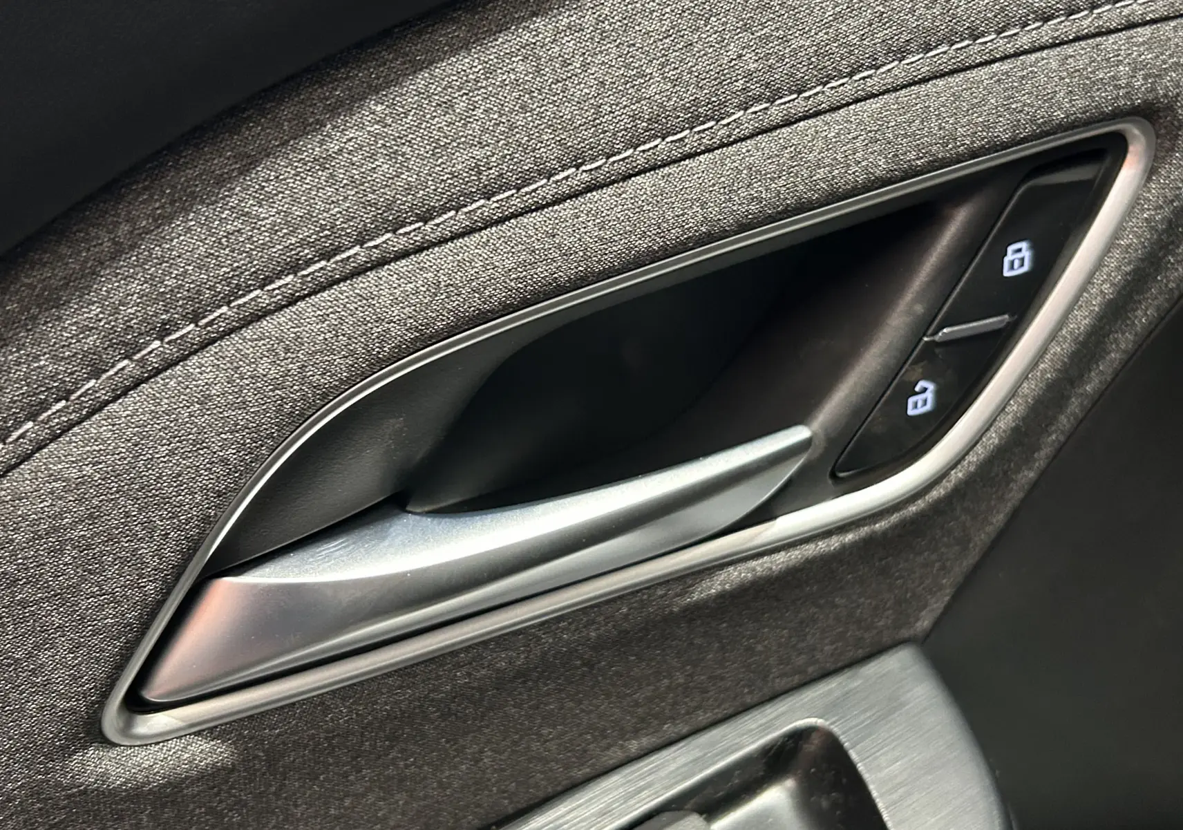 Poignée intérieure de porte côté conducteur du MG ZS Hybrid+ 2025 en tissu gris avec boutons de verrouillage.