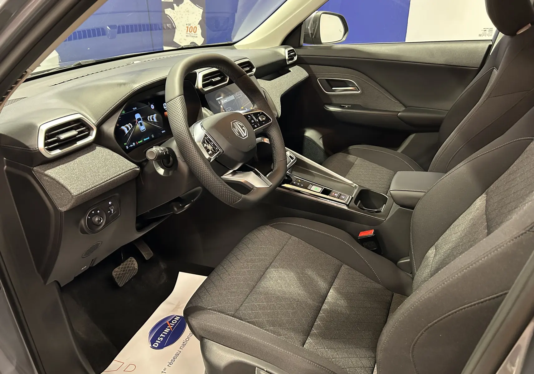 Intérieur côté conducteur du MG ZS Hybrid+ 2025 en Hampstead Grey, avec volant multifonction et sièges tissu chauffants.