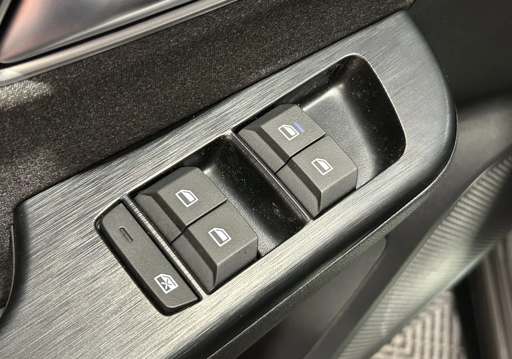 Gros plan sur les commandes électriques des vitres côté conducteur du MG ZS Hybrid+ 2025 en finition Hampstead Grey.