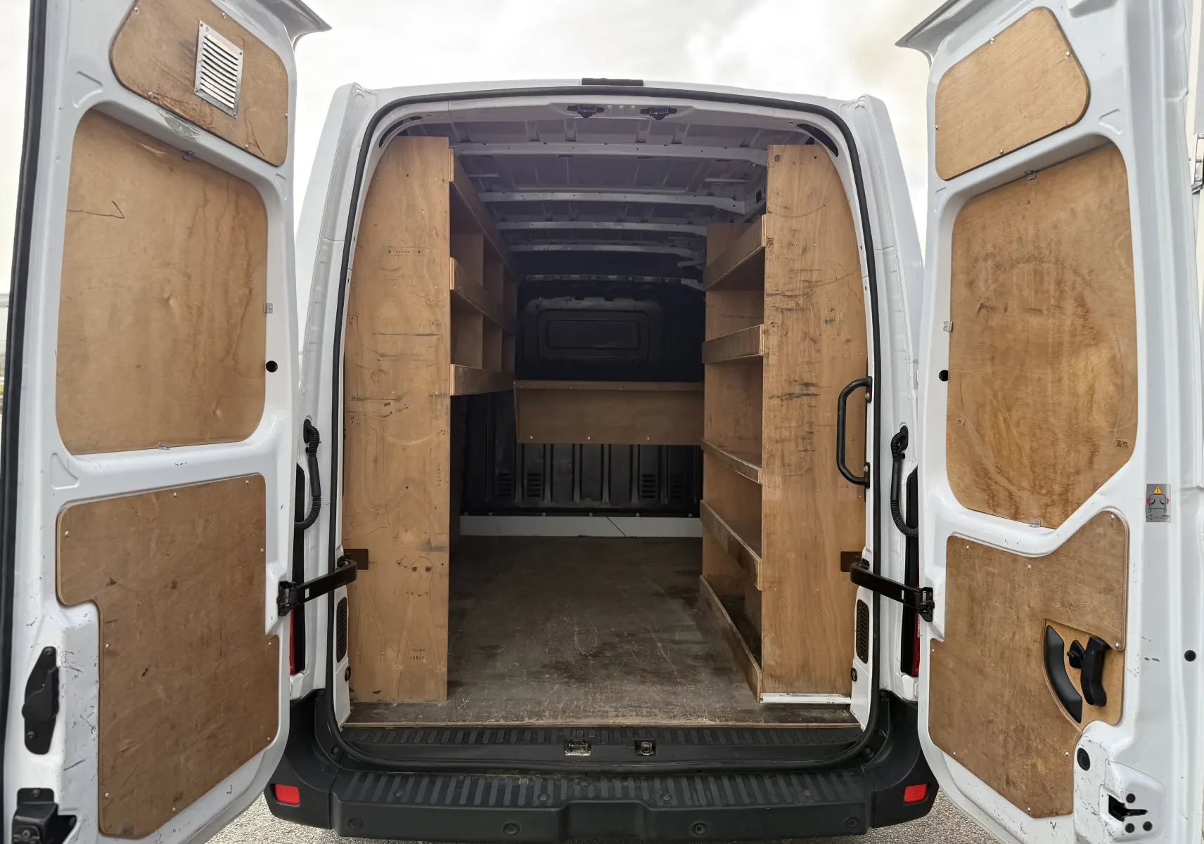 Vue arrière ouverte d'un Renault Master blanc 2020 avec aménagements en bois dans l'espace de chargement.