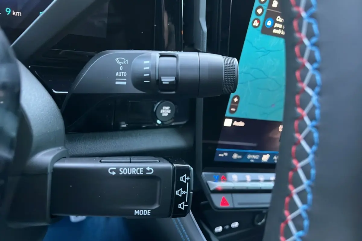 Gros plan sur les commandes au volant avec surpiqûres tricolores du Renault Rafale 4x4 300 blanc nacré toit noir.