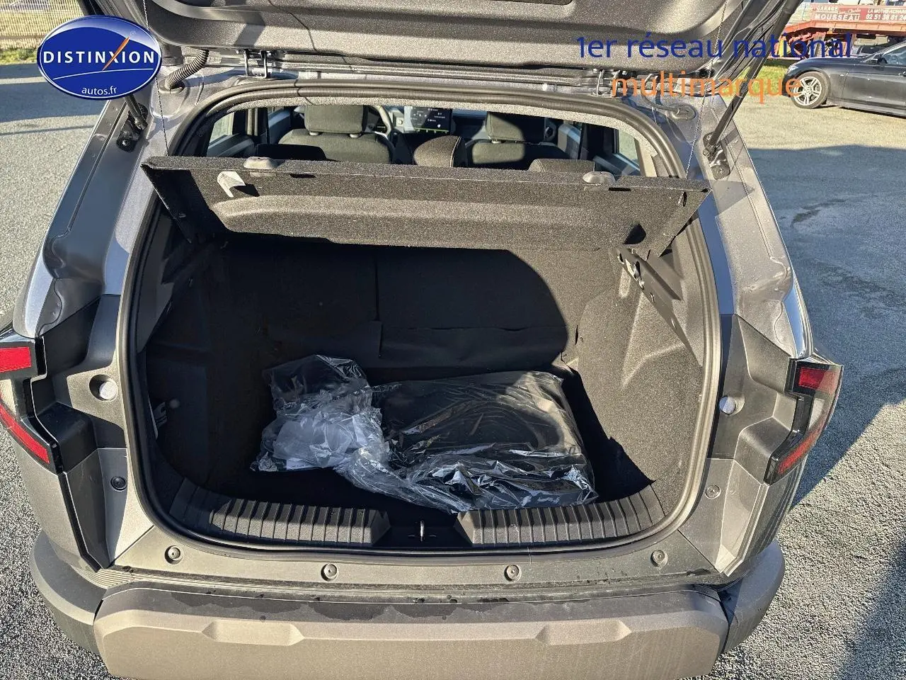 Coffre ouvert vu de l'arrière d'un Dacia Duster gris schiste 2025, montrant l'espace de chargement vide avec cache-bagages relevé.