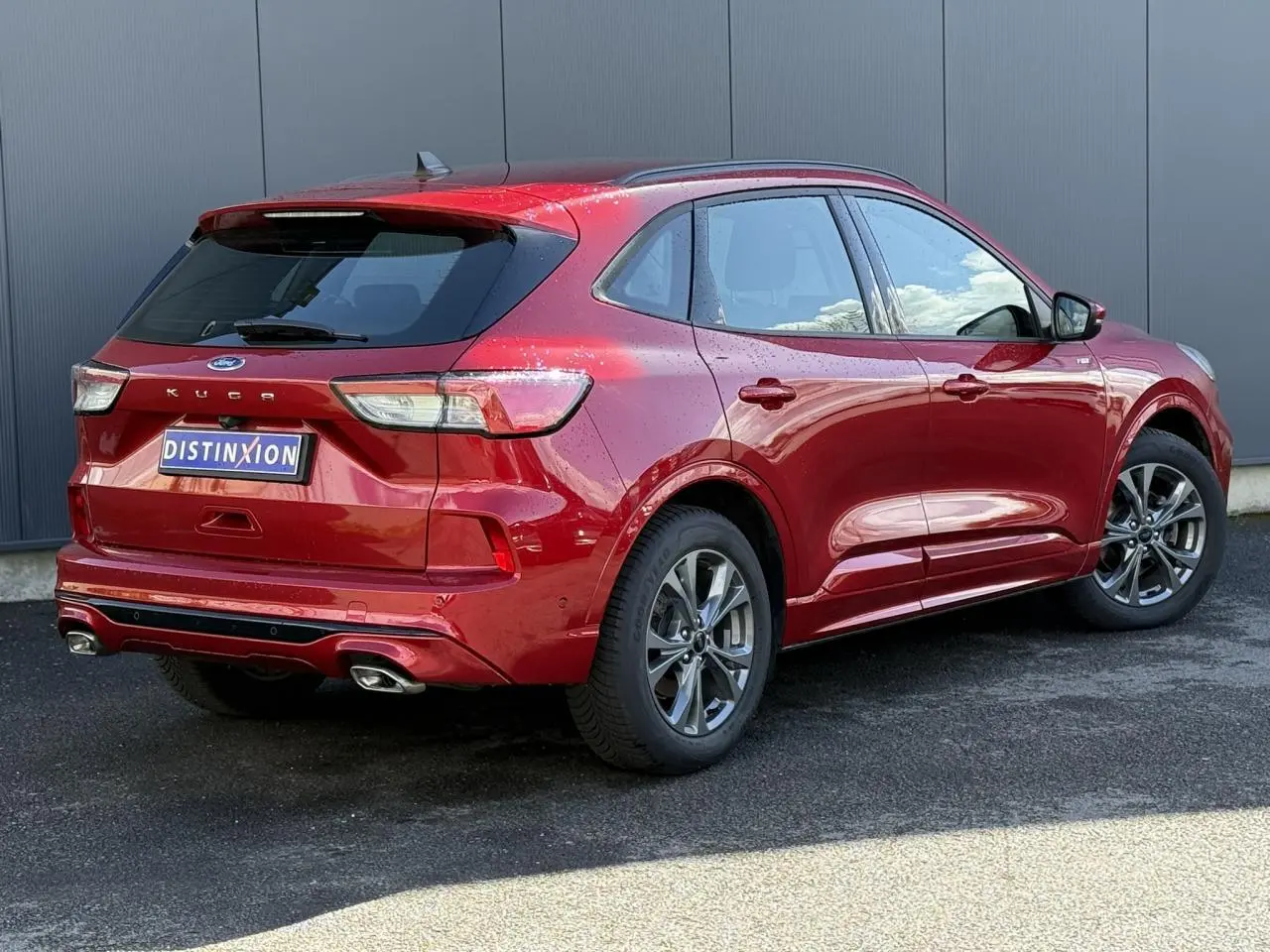 Vue 3/4 arrière droite du Ford Kuga rouge Lucifer 2024 avec double sortie d'échappement et jantes alliage 18 pouces.