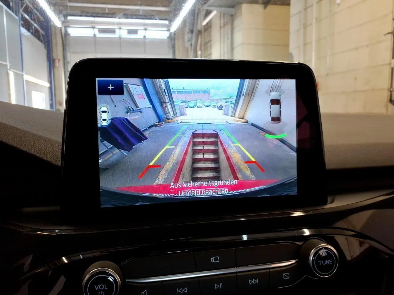 Écran tactile intérieur montrant la caméra de recul du Ford Kuga rouge, avec lignes de guidage colorées.