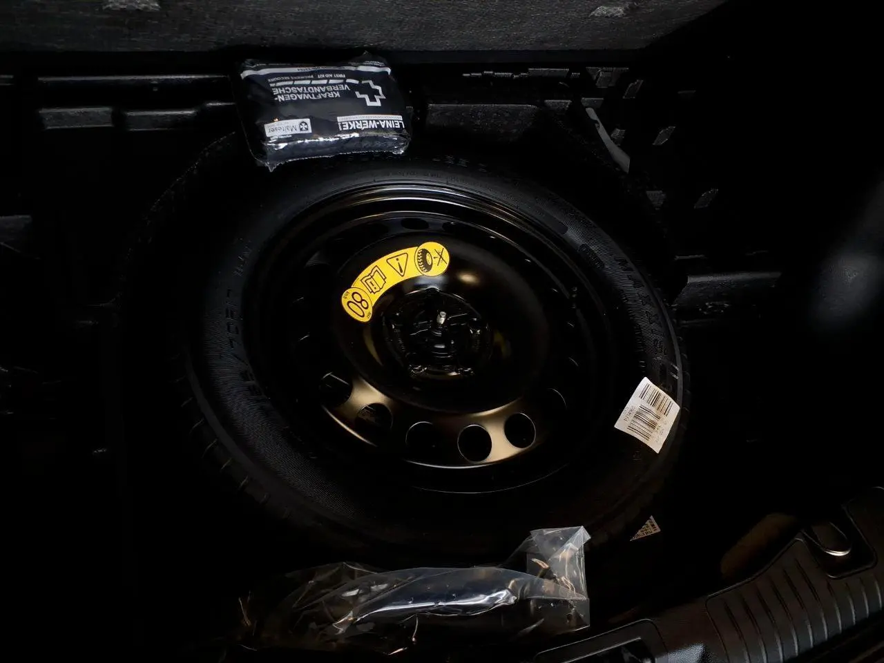 Gros plan sur la roue de secours galette noire dans le coffre du Ford Kuga 2024 Rouge Lucifer.