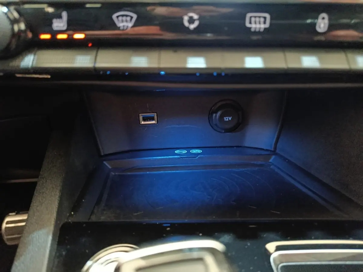 Gros plan sur la console centrale du Peugeot 3008 bleu, avec prise USB, prise 12V et surface de charge sans fil.