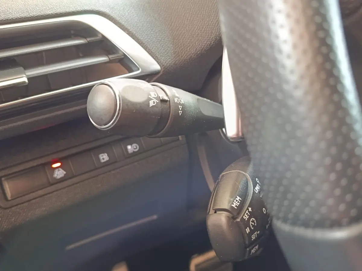 Détail intérieur du Peugeot 3008 bleu 2020 montrant la commande des phares et le régulateur de vitesse près du volant.