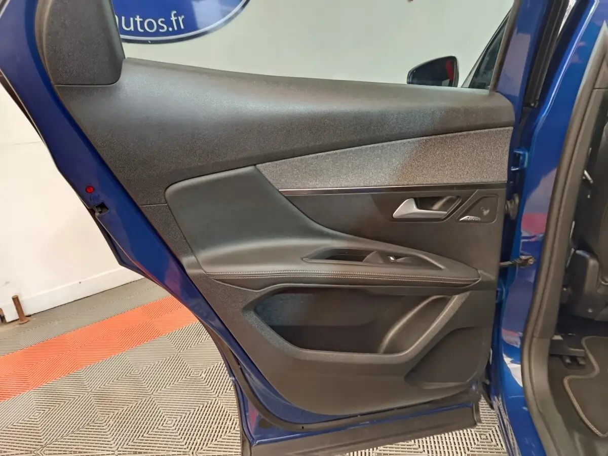 Vue intérieure de la porte arrière droite bleu du Peugeot 3008 1.6 HYBRID 225 GT Pack avec garniture noire et commandes fenêtres.