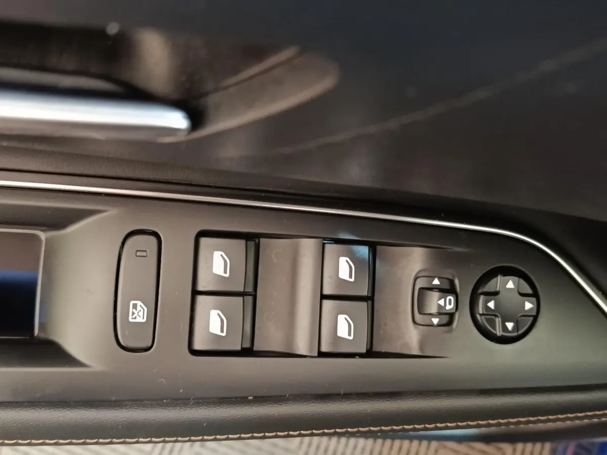 Gros plan sur les commandes de lève-vitres et rétroviseurs côté gauche intérieur d'une Peugeot 3008 bleu hybride rechargeable.