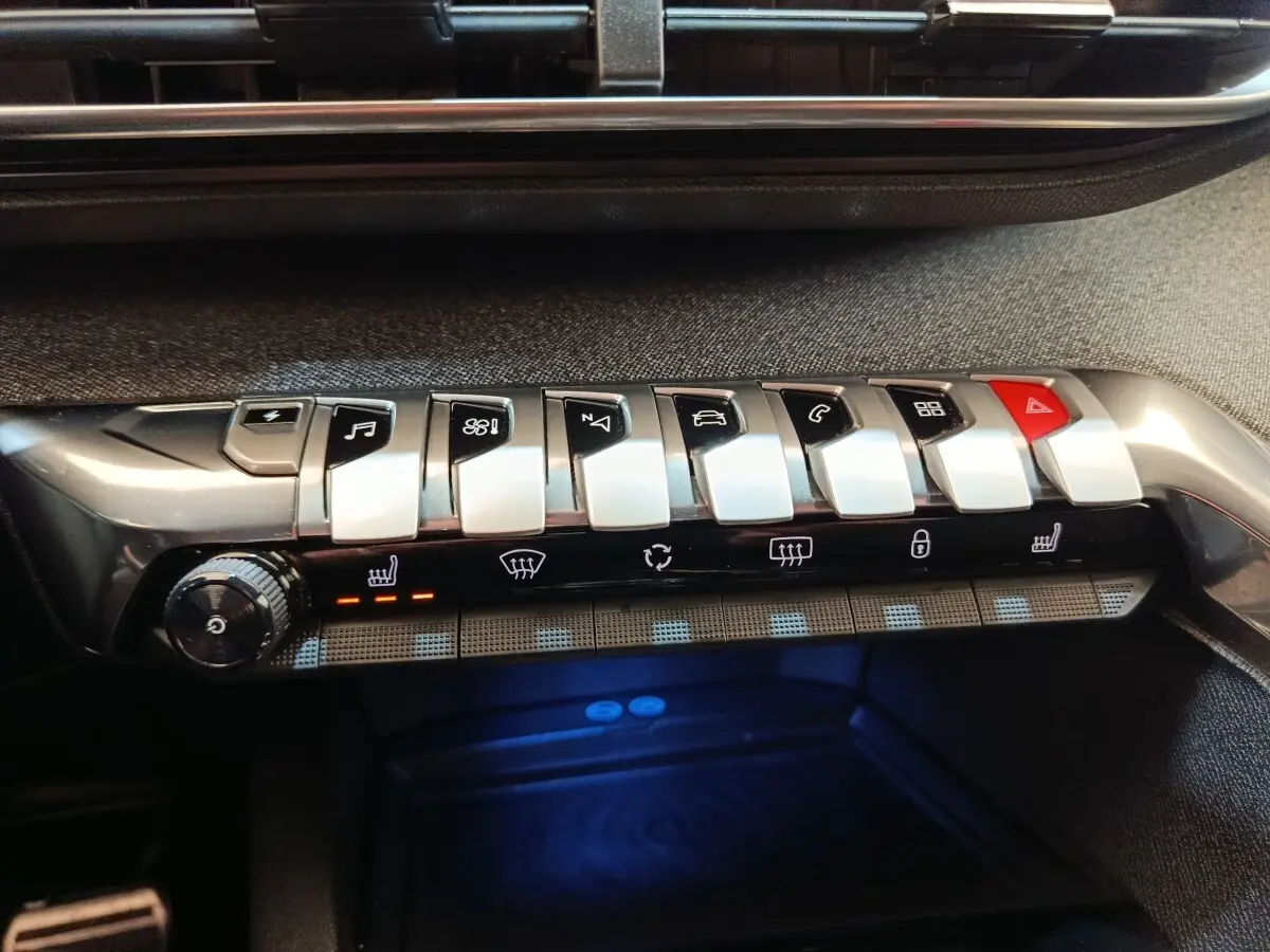 Gros plan sur la console centrale avec les boutons piano argentés et le bouton rouge de warning du Peugeot 3008 bleu hybride.