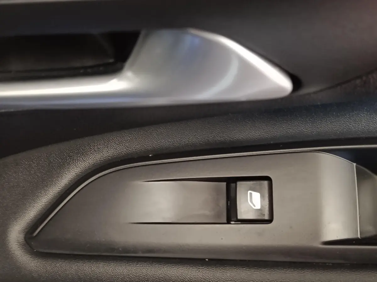 Détail du bouton de commande de lève-vitre côté gauche intérieur d’un Peugeot 3008 bleu hybride rechargeable.