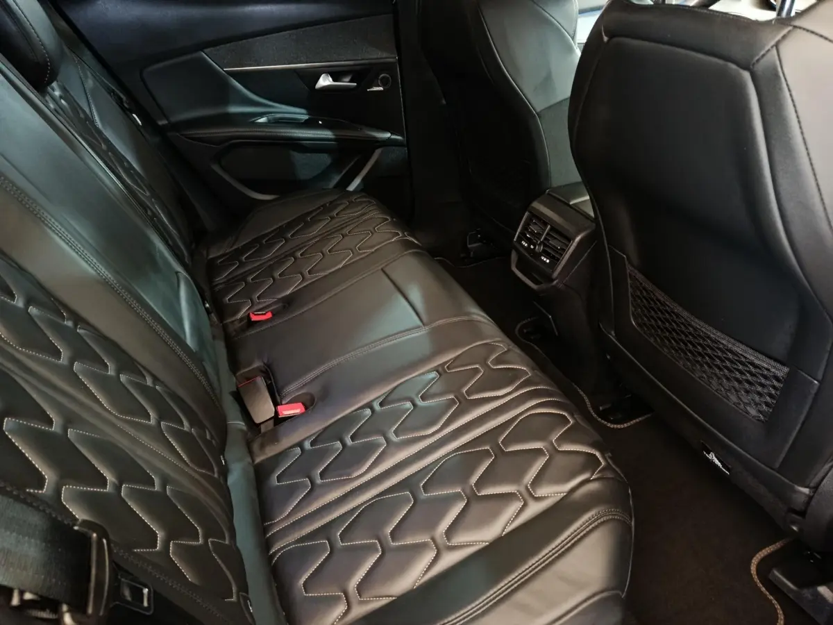 Vue intérieure arrière côté gauche du Peugeot 3008 1.6 Hybrid 225 GT Pack, sièges en cuir noir avec surpiqûres.