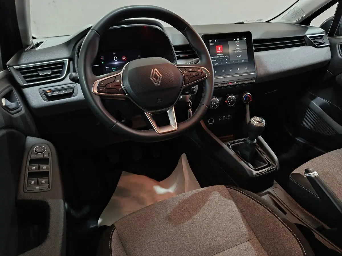 Vue intérieure avant de la Renault Clio noire 2025, volant cuir multifonctions et écran tactile central visible.