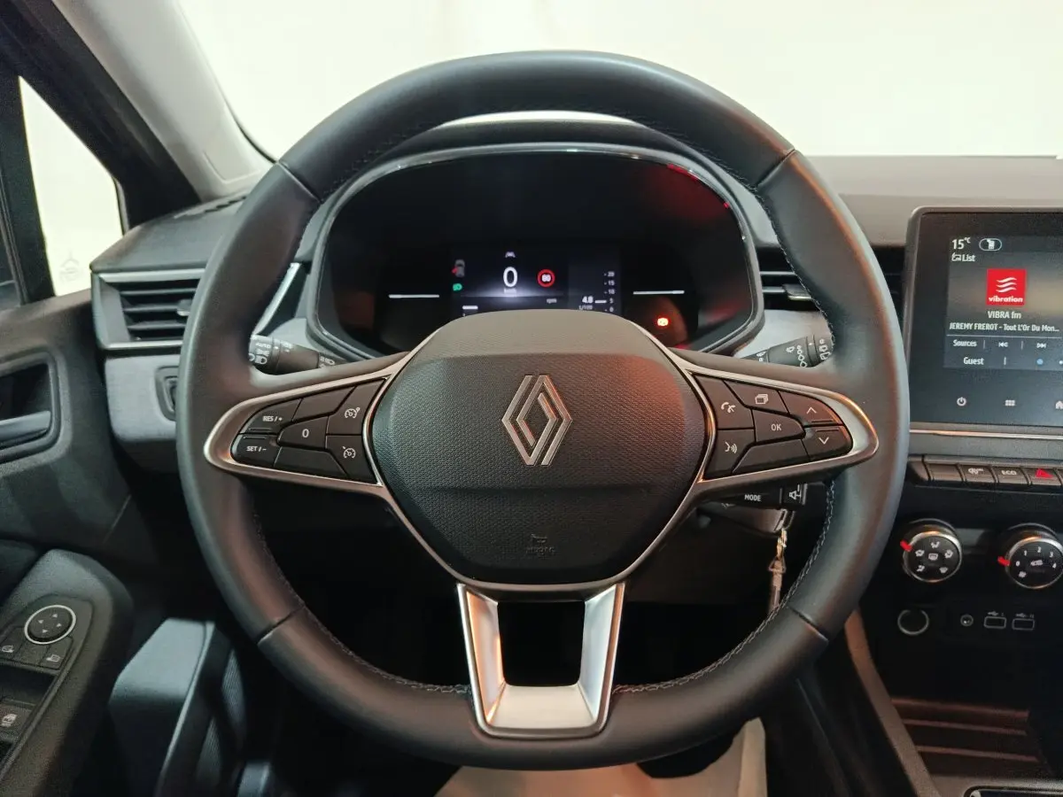 Vue intérieure centrée sur le volant cuir noir multifonctions de la Renault Clio 2025 avec tableau de bord numérique et écran tactile.