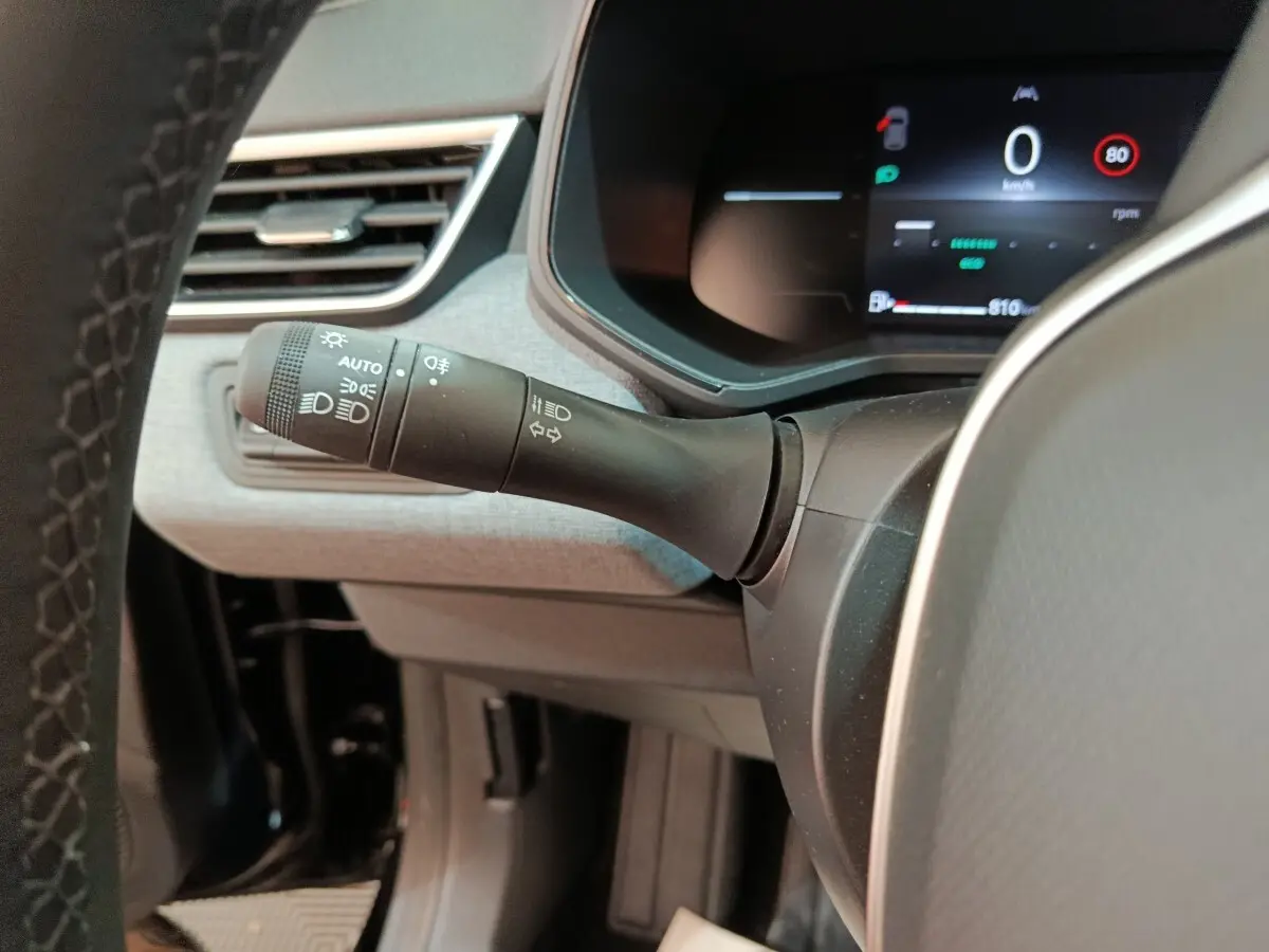 Gros plan sur la manette des phares et clignotants à gauche du volant dans l’habitacle d’une Renault Clio noire 2025.