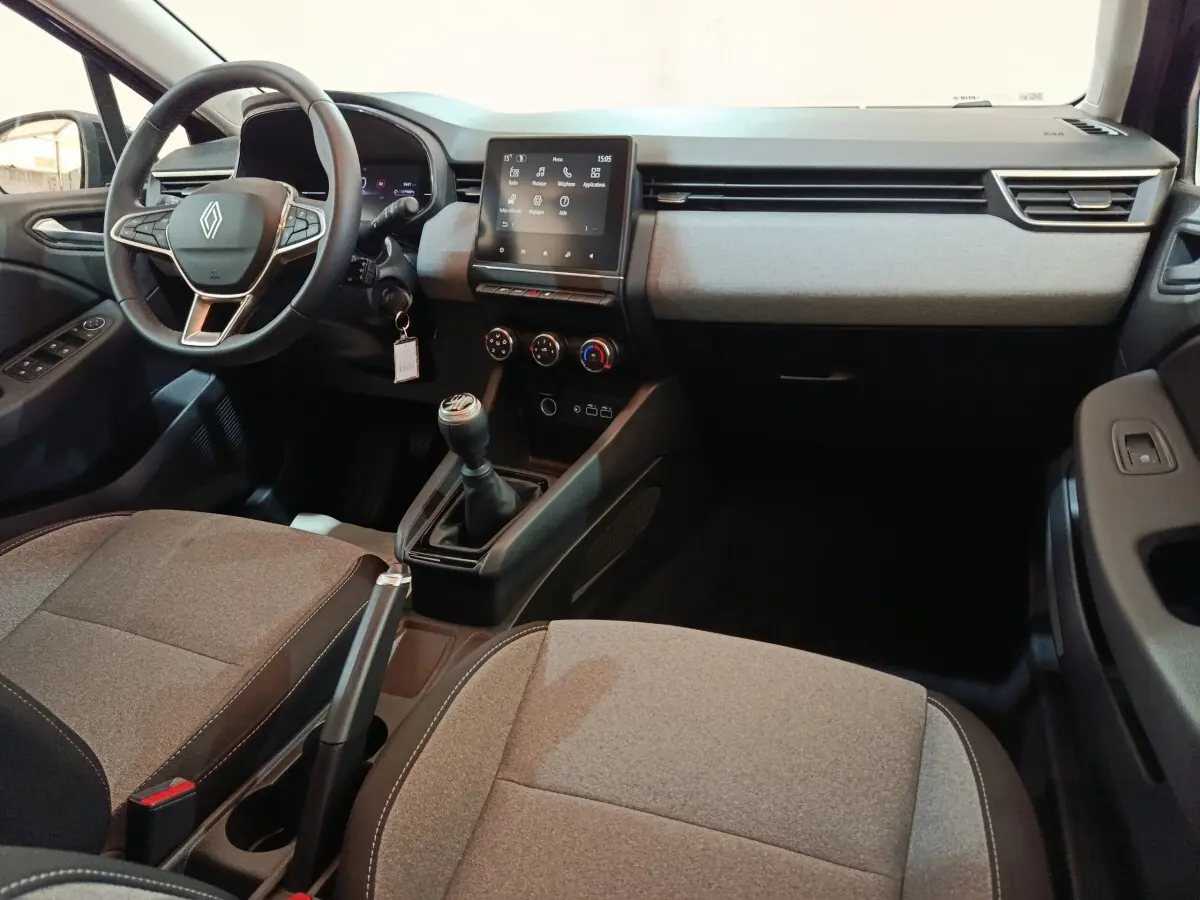 Vue intérieure avant droite de la Renault Clio 2025, tableau de bord moderne avec écran tactile et volant multifonctions.