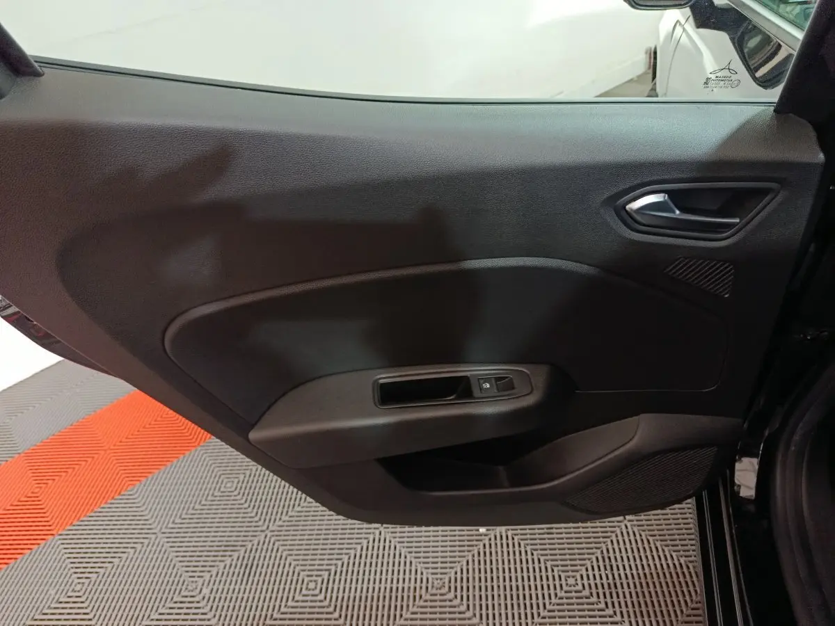 Vue intérieure côté gauche de la porte arrière noire de la Renault Clio 2025 avec poignée et commande de fenêtre électrique.