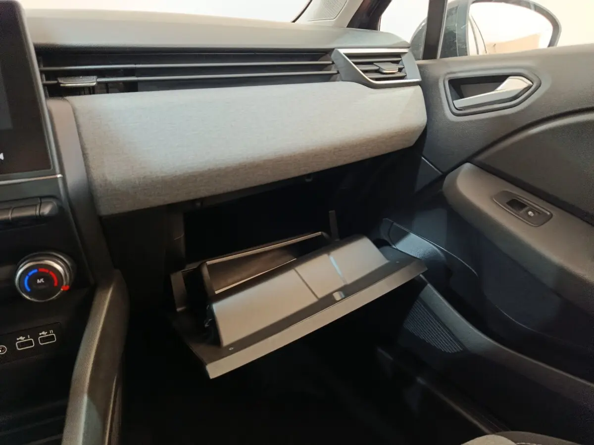 Intérieur côté passager de la Renault Clio noir 2025, avec boîte à gants ouverte et tableau de bord gris clair.