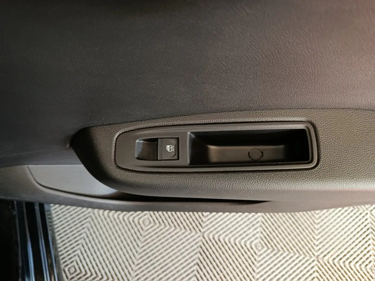 Gros plan sur la commande de lève-vitre électrique côté intérieur d'une Renault Clio noire, finition Evolution Blue dCi 100.