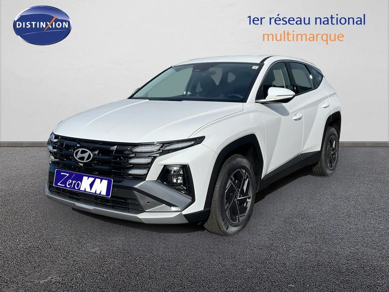 Hyundai Tucson blanc Atlas en 3/4 avant droit, avec calandre noire et jantes alliage noires distinctives.