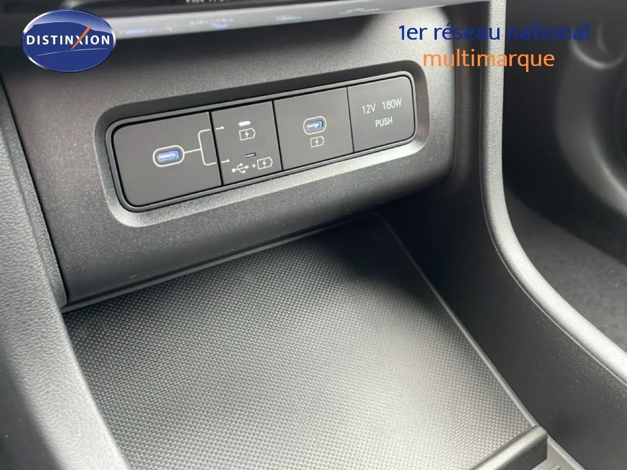 Vue rapprochée de la console centrale du Hyundai Tucson 2026 montrant les ports USB et prise 12V, intérieur noir.