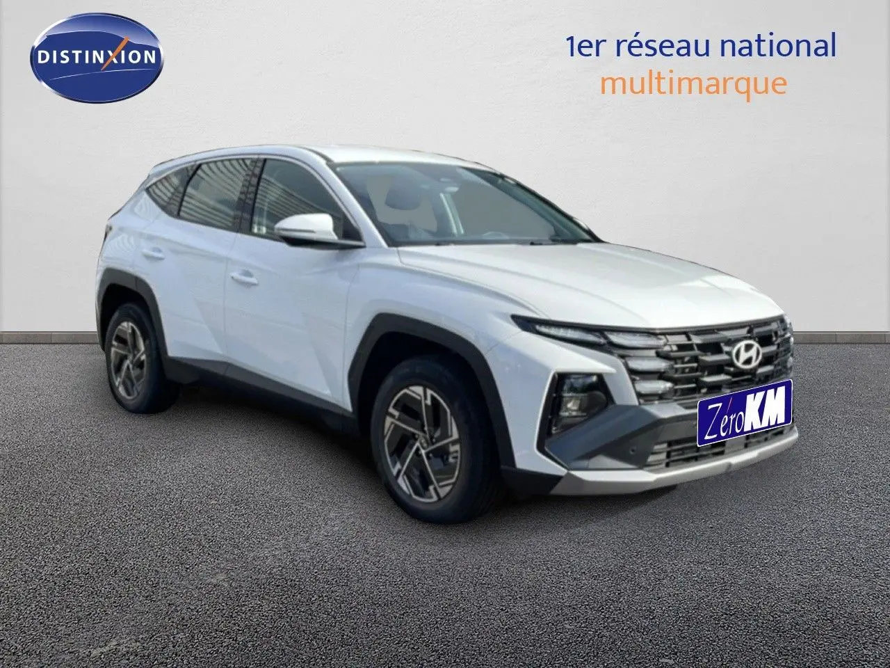 Hyundai Tucson blanc atlas en 3/4 avant droit, SUV hybride avec calandre distinctive et jantes bi-ton.