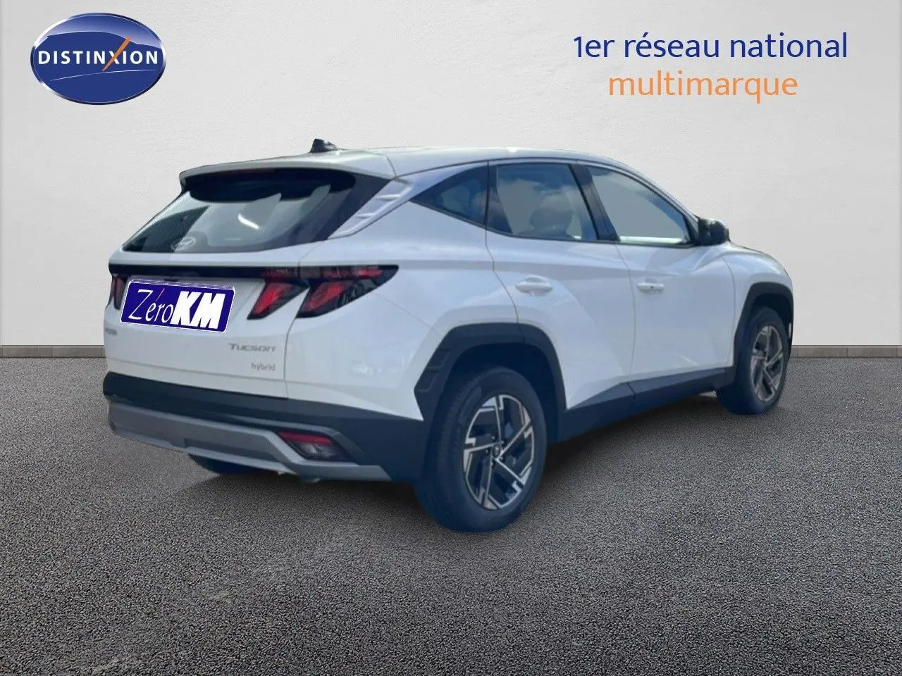 Vue 3/4 arrière droite d'un Hyundai Tucson blanc Atlas hybride avec jantes bi-ton et feux arrière distinctifs.