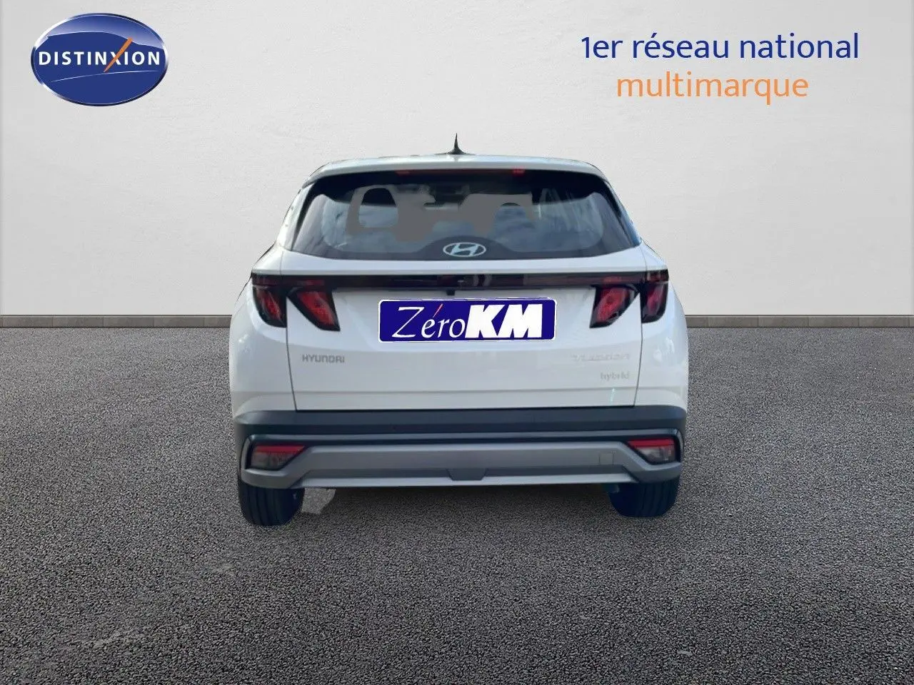 Vue arrière d'un Hyundai Tucson blanc Atlas 2026 hybride essence avec feux arrière sombres et plaque Zéro KM.