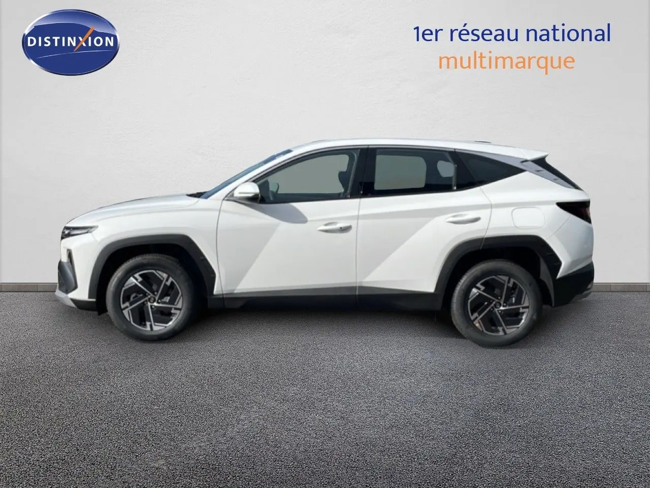 Vue de profil côté gauche d'un Hyundai Tucson blanc Atlas 2026 avec jantes bi-ton et lignes anguleuses marquées.