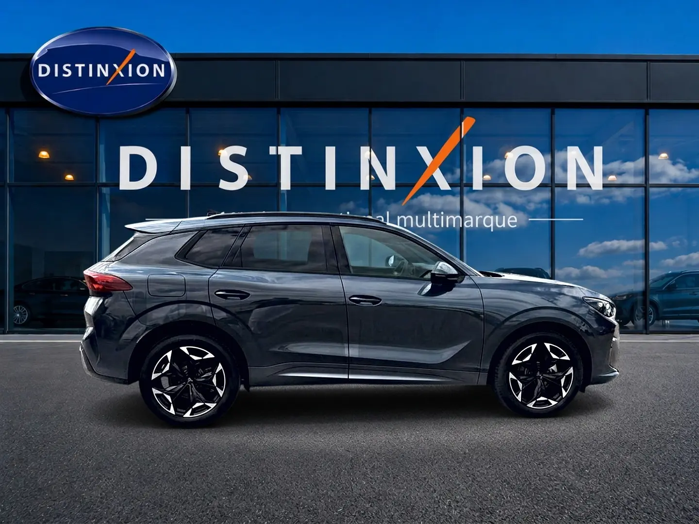 Vue latérale droite du SUV CUPRA TERRAMAR gris Timanfaya avec jantes noires et détails modernes devant une vitrine Distinxion.