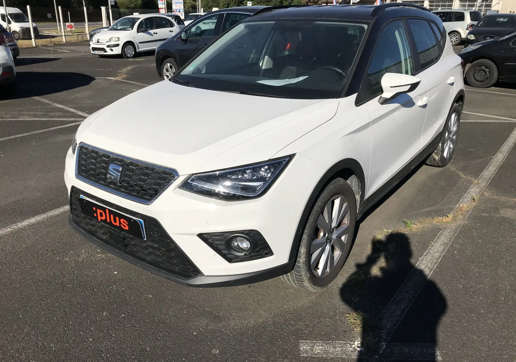 SEAT Arona blanc avec toit noir en vue 3/4 avant droit, mettant en valeur ses phares anguleux et sa calandre noire.