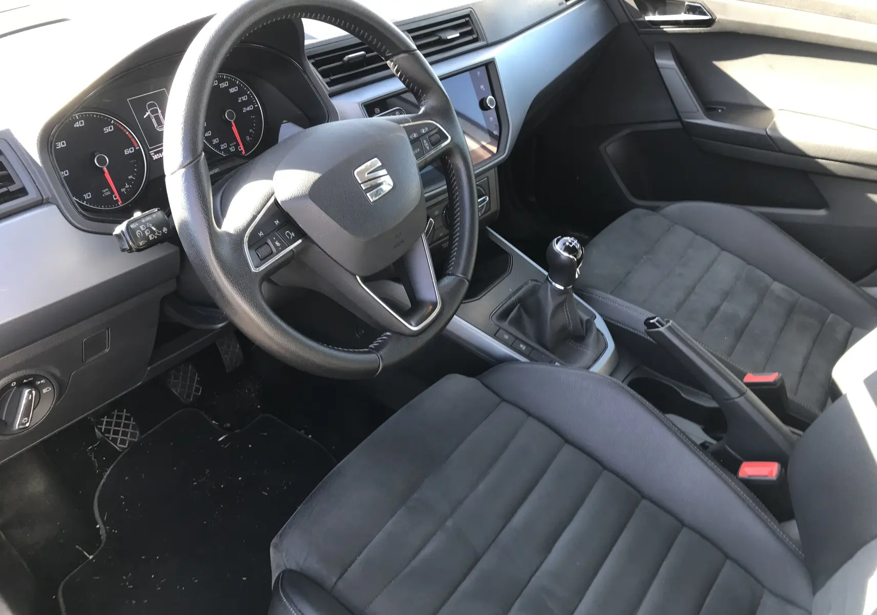 Vue intérieure côté conducteur de la SEAT Arona 2019 avec volant cuir, tableau de bord moderne et levier de vitesses manuel.