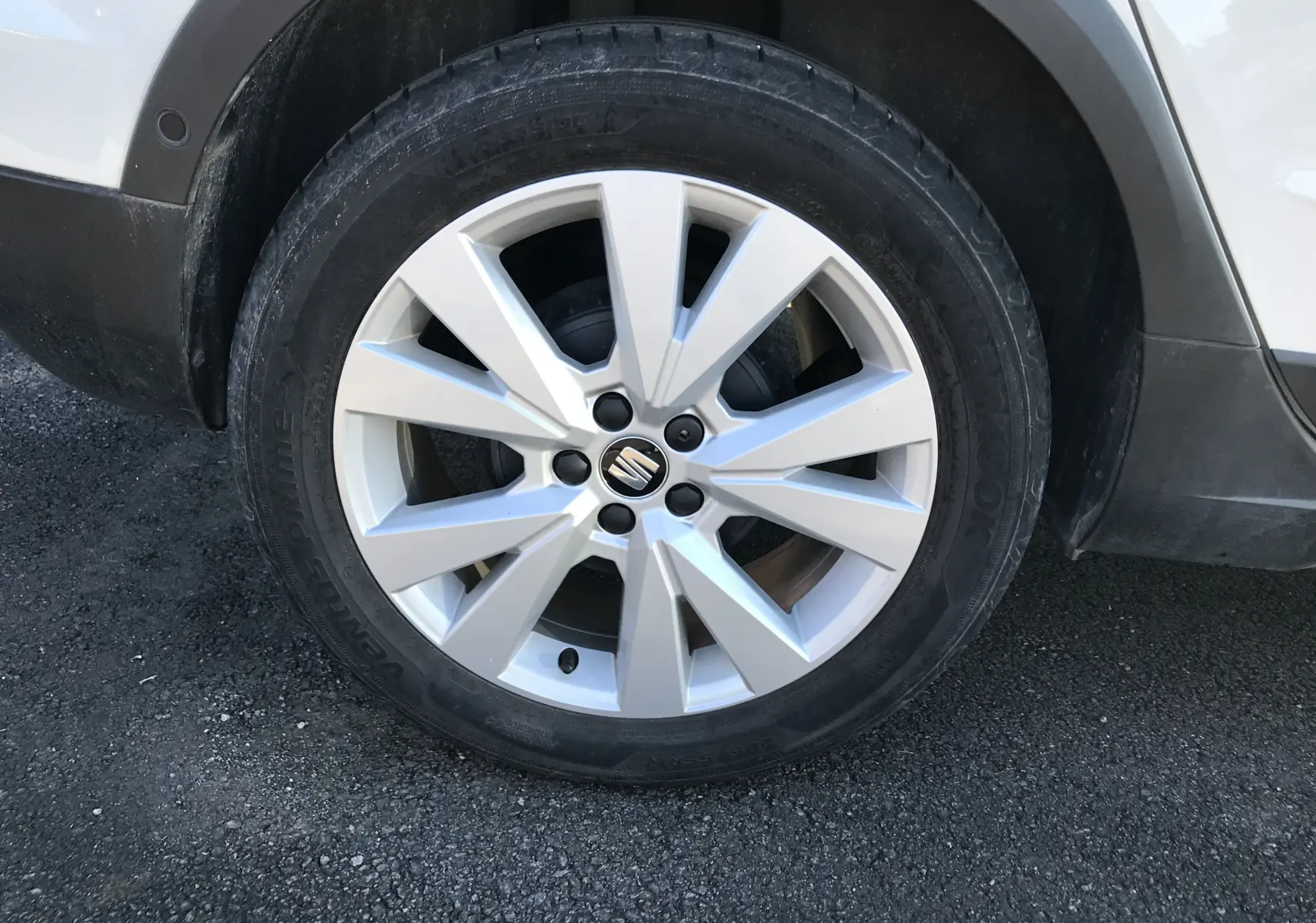 Gros plan sur la roue avant droite d'un SEAT Arona blanc toit noir, mettant en valeur la jante en alliage argentée.