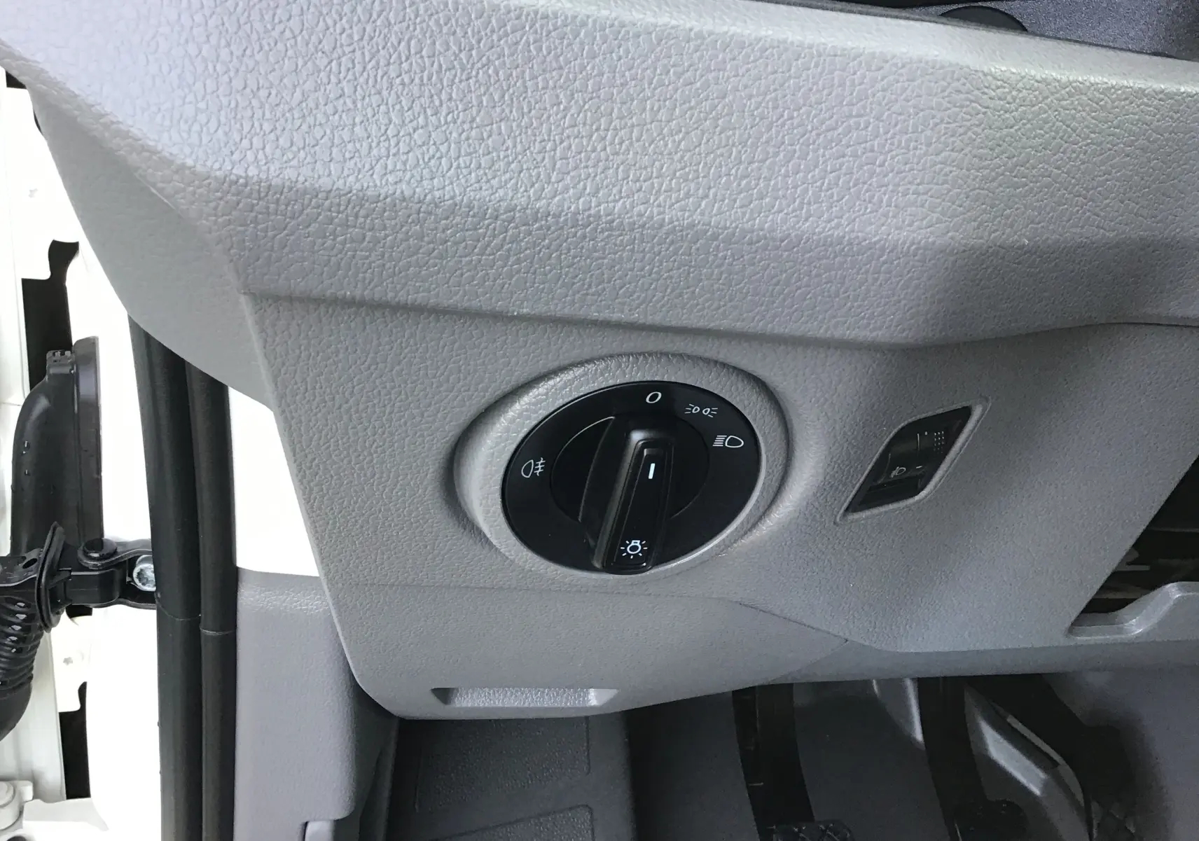Gros plan sur le bouton de commande des phares dans l'habitacle gris clair du Volkswagen Crafter blanc L3H3 2021.
