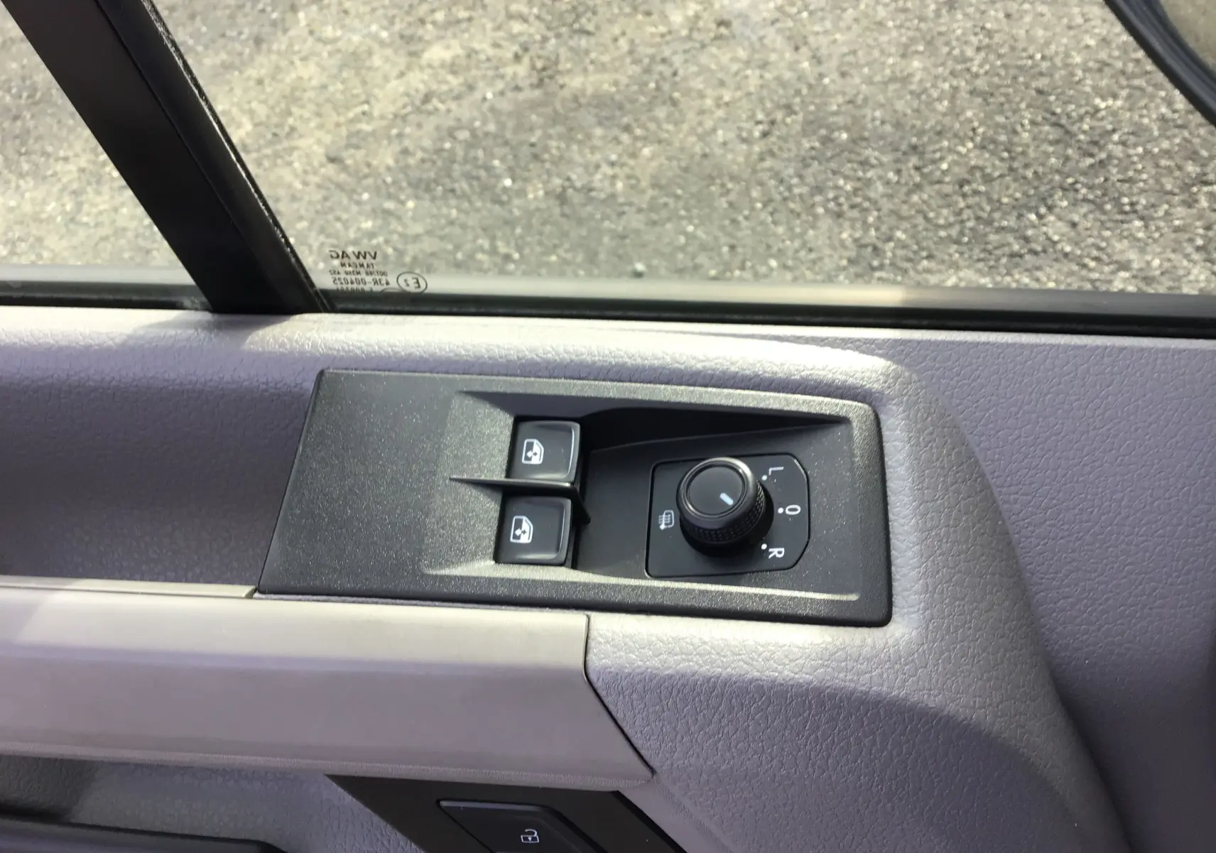 Gros plan sur les commandes de réglage des rétroviseurs et des vitres côté conducteur du Volkswagen Crafter blanc.