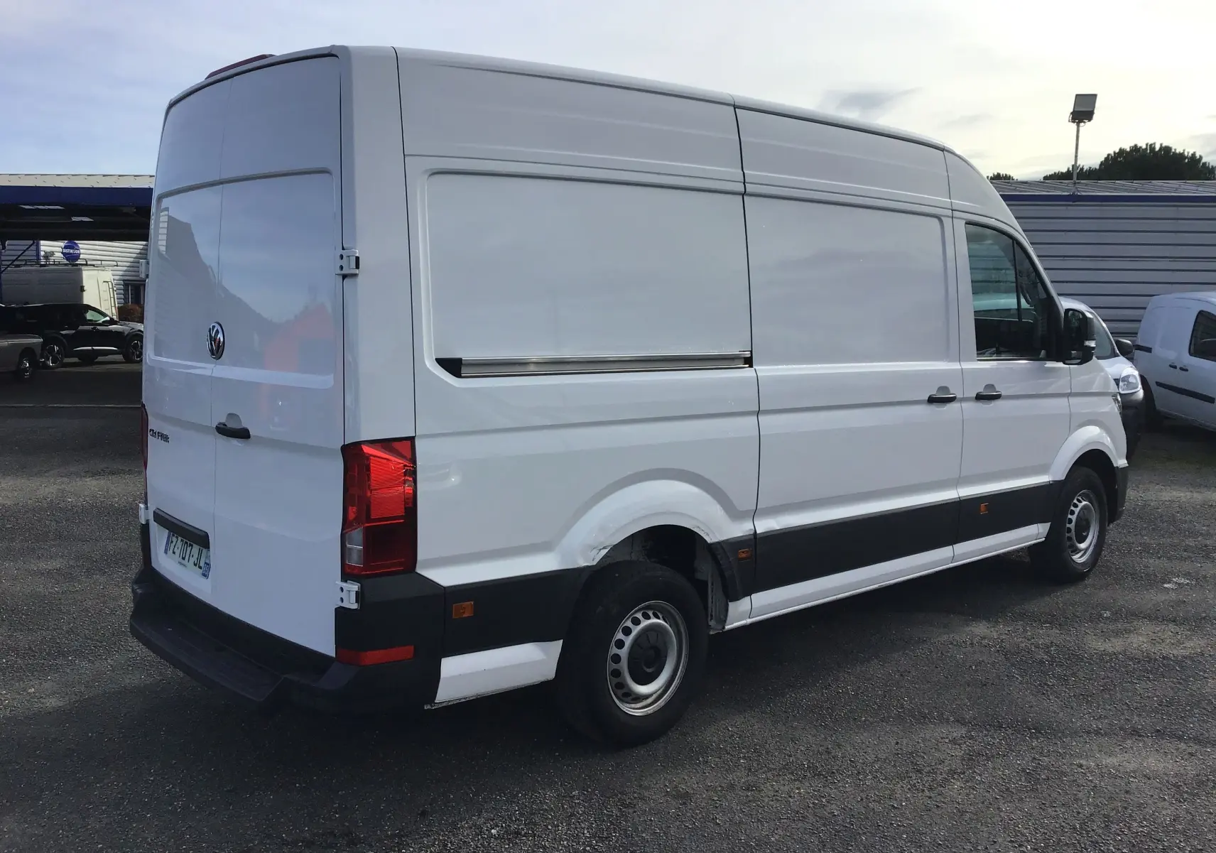 Vue 3/4 arrière droite d'un Volkswagen Crafter blanc L3H3, fourgon utilitaire avec porte latérale coulissante fermée.