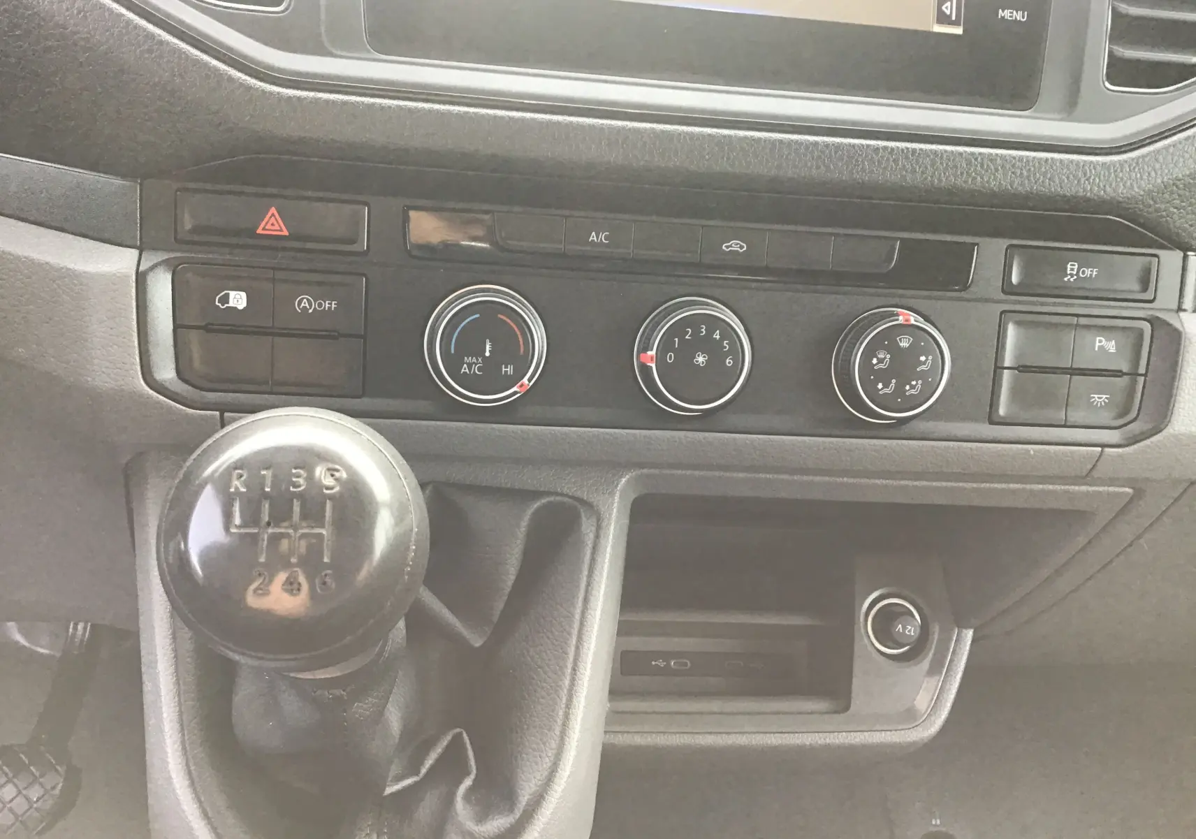 Gros plan sur la console centrale du Volkswagen Crafter blanc, mettant en valeur le levier de vitesses manuel et les commandes de climatisation.