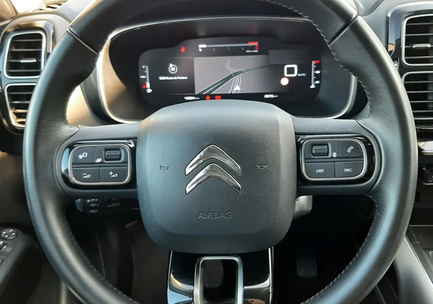 Vue rapprochée du volant noir du Citroën C5 Aircross 2021 avec commandes intégrées et tableau de bord numérique.