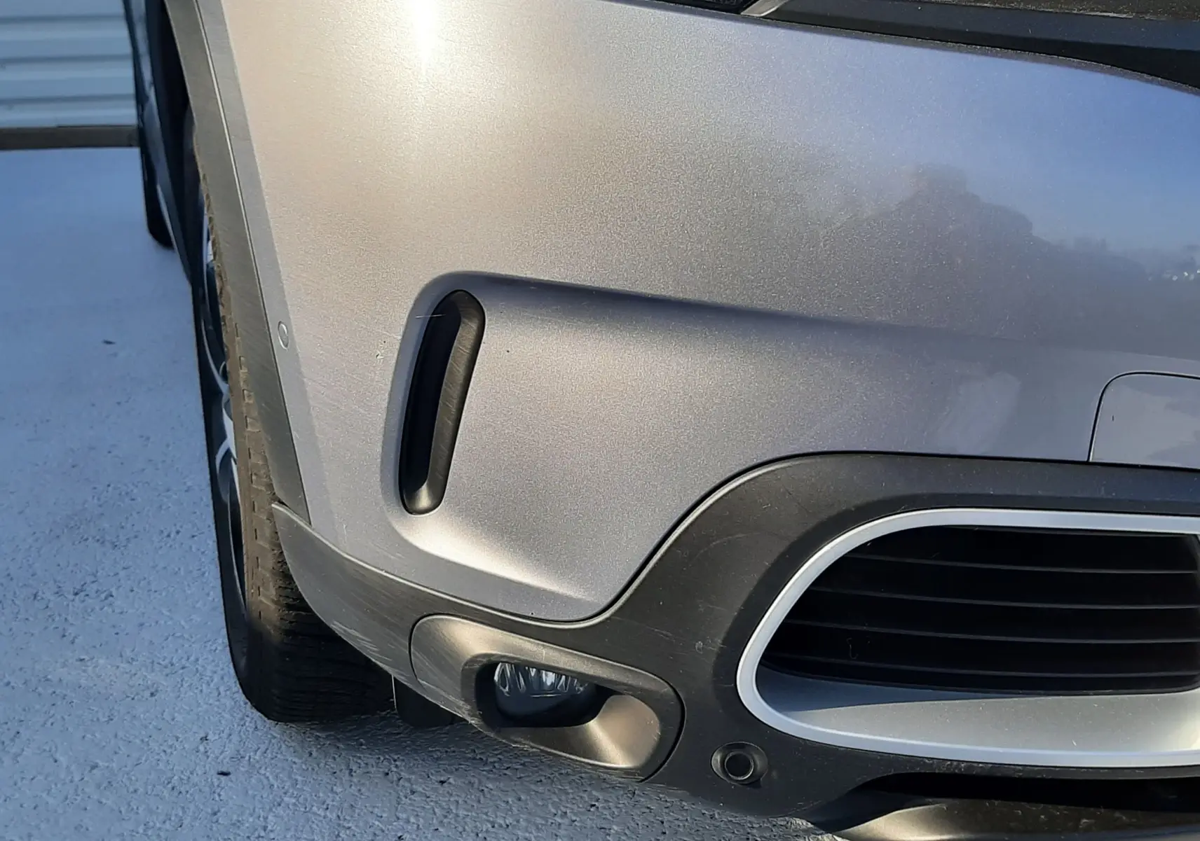 Gros plan sur l'avant gauche gris Artense du Citroën C5 Aircross 2021, mettant en valeur le phare et le pare-chocs.