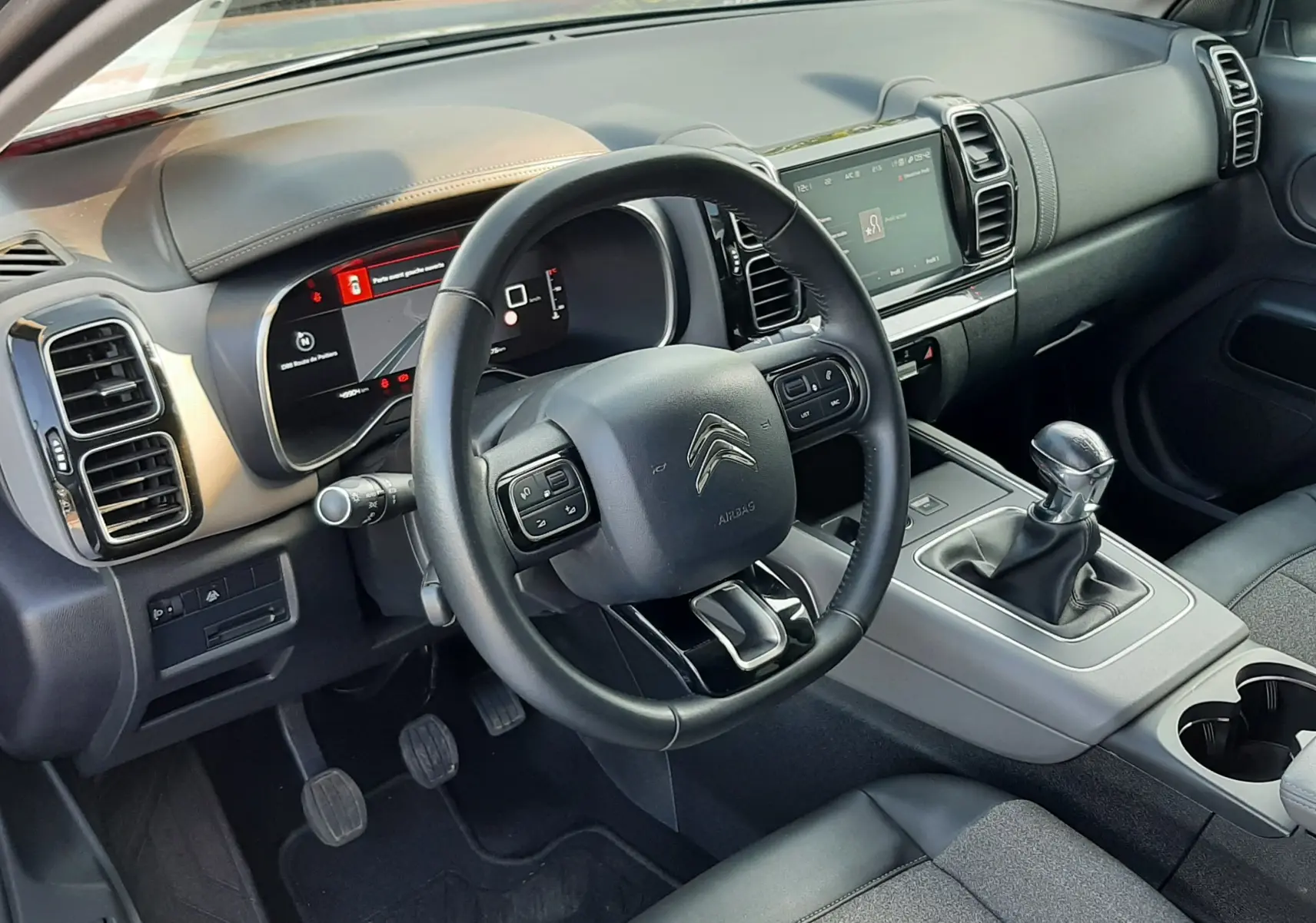Vue intérieure côté conducteur du Citroën C5 Aircross 2021 avec tableau de bord moderne et levier de vitesse manuel.