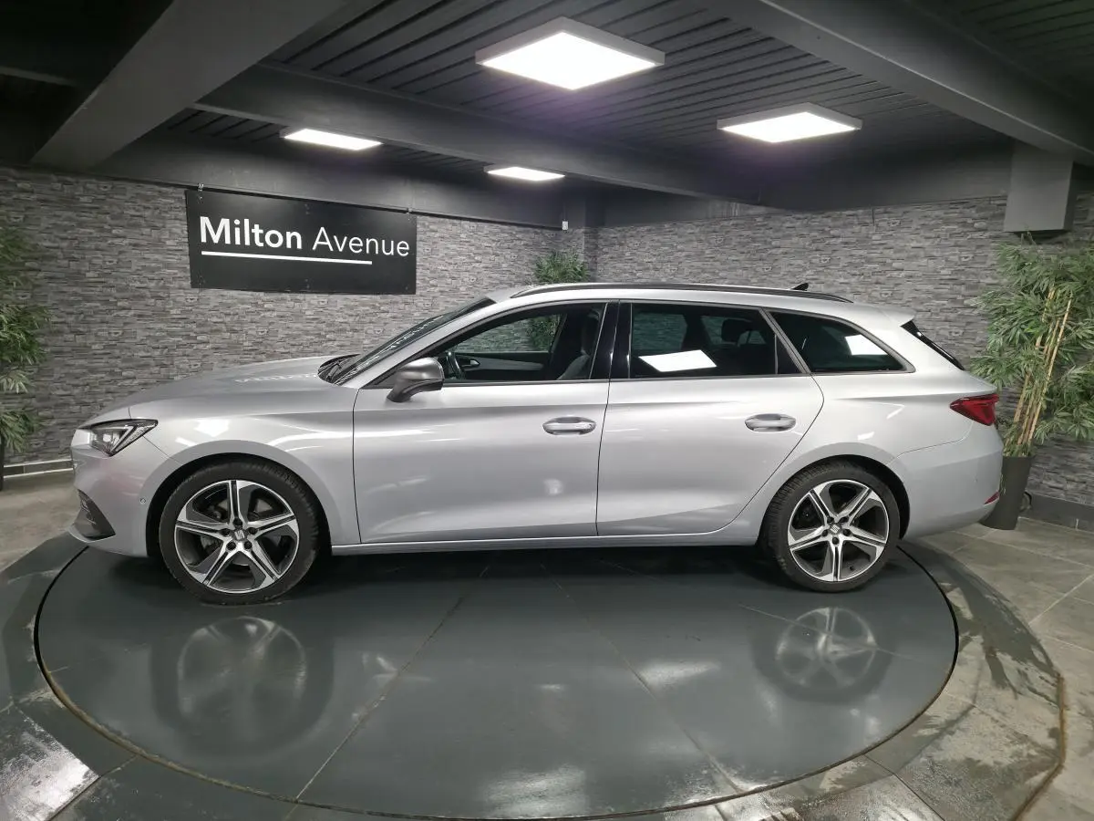 Profil droit d'un break SEAT Leon Sportstourer gris urbain 2022 avec jantes alliage 18 pouces dans un showroom.