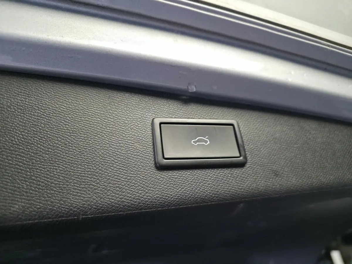 Bouton d'ouverture électrique du hayon sur la garniture intérieure noire du coffre d'un SEAT Leon Sportstourer gris.